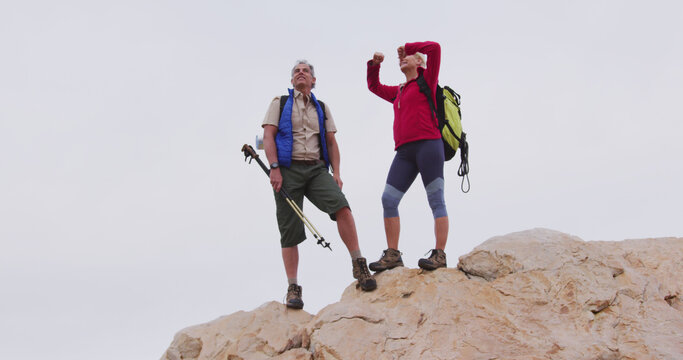 Senior couple enjoys a triumphant moment during a mountain trek.