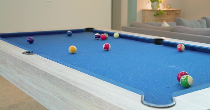 Pool table occupying center of living room, featuring blue felt, scattered billiard balls