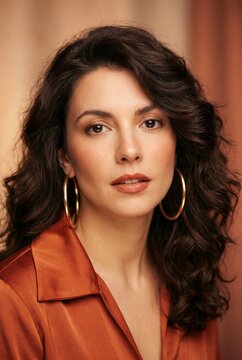 Portrait mode ann&eacute;es 70 : femme brune aux cheveux boucl&eacute;s en combinaison orange