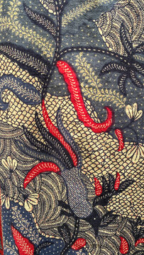Richly patterned batik fabric featuring intricate floral embroidery on a deep blue background