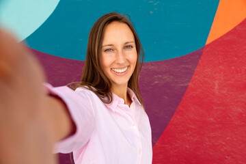 Smiling woman taking a selfie against a colorful mural © luisrojasstock