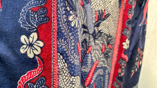 Richly patterned batik fabric featuring intricate floral embroidery on a deep blue background