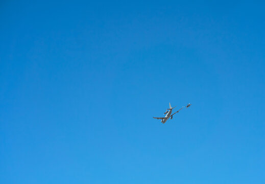 A large refueling aircraft flies in formation with two single-engine fighter jets for in-flight refueling.