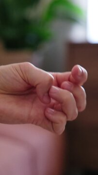 Close-up of a nervous person picking at their fingernails and fingers, showing signs of anxiety, stress, or impatience, vertical video.