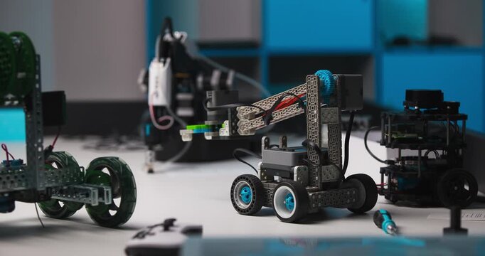 Programmable wheeled robots with articulated mechanisms arranged on a workbench, central robot changing position in a technology workshop