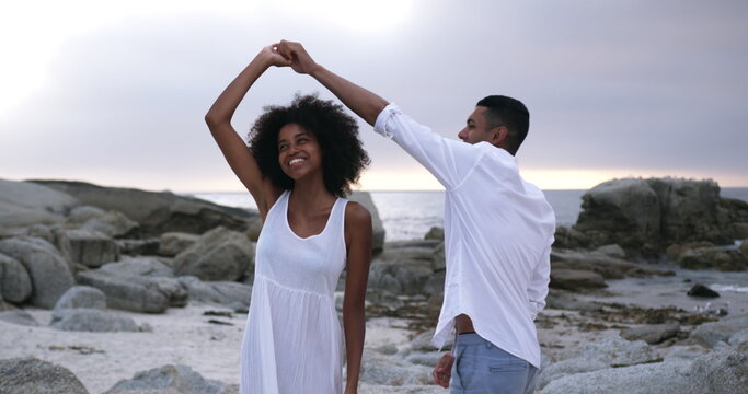 Side view of romantic young couple dancing together on the beach