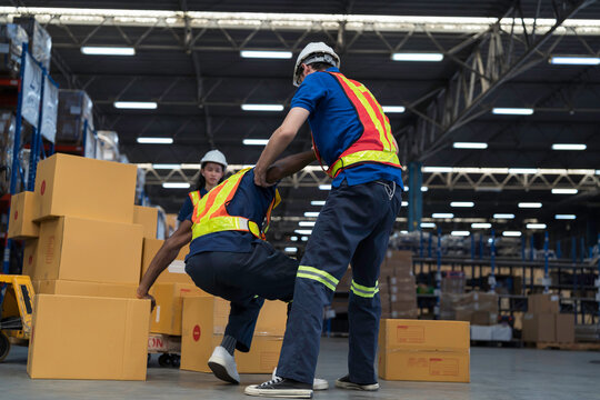Warehouse worker accident at work. Warehouse worker catches and assists after cardboard boxes collapsed fell from wooden pallet cart, occupational workplace safety accident concept