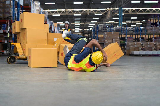 Warehouse worker accident at work. Warehouse worker falling down on concrete floor after cardboard boxes collapsed fell from wooden pallet cart, occupational workplace safety accident concept