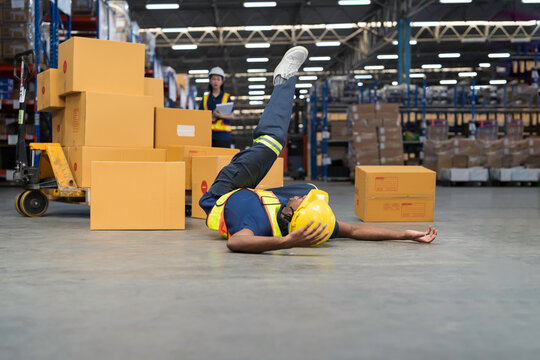 Warehouse worker accident at work. Warehouse worker falling down on concrete floor after cardboard boxes collapsed fell from wooden pallet cart, occupational workplace safety accident concept