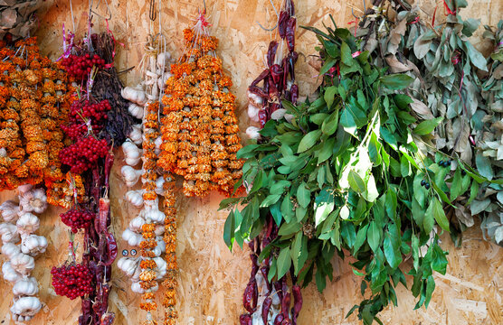 Hanging dried herbs and spices market wall display. Rustic wooden background with organic garlic and flowers