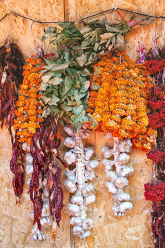 Hanging dried herbs and spices market wall display. Rustic wooden background with organic garlic and flowers