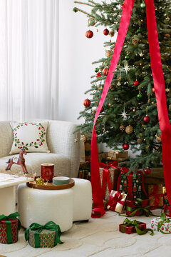 Cozy living room with Christmas tree, red ribbon, presents, and white sofa. Festive holiday scene for greeting cards, winter design, and banners