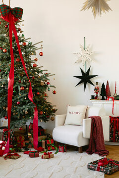 Festive interior featuring a decorated tree, presents, armchair, and star decor. Warm mood for holiday card, website banner, and seasonal sale