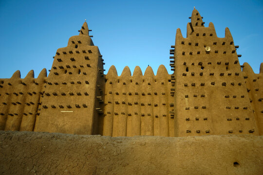 Two towers of the Great Mosque rising above a mud wall against a deep blue sky, Mopti Region, Djenne, Mali