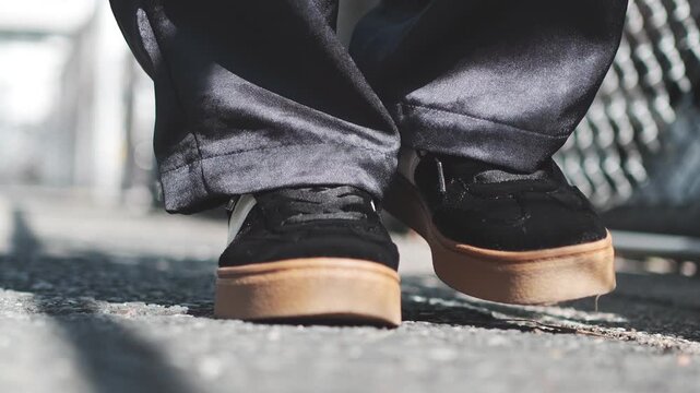 Close Up of Black Sneakers Walking on Asphalt Sidewalk in Slow Motion