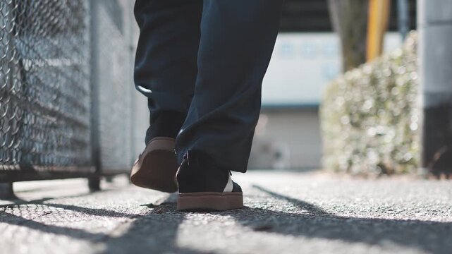 Close Up of Black Sneakers Walking on Asphalt Sidewalk in Slow Motion