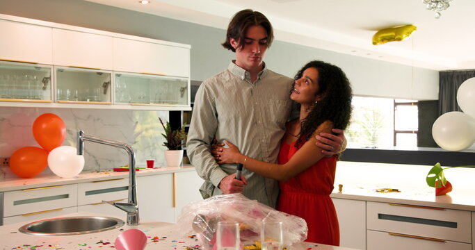 Happy white and multiracial couple cleaning decorations, confetti from floor and countertop after pa