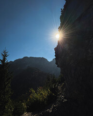 Krajobraz górski. Słońce wychodzące za skały na szlaku górskim. Szlak na Sarnią Skałę. Tatry jesienią. Plakat. Polskie góry. © Anita