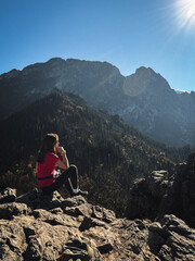 Kobieta podziwia górskie krajobrazy, zachwyca się widokami, odpoczywa po wędrówce. Giewont widziany z Sarniej Skały. Tatry jesienią. Górskie krajobrazy. Plakat. Polskie góry. © Anita
