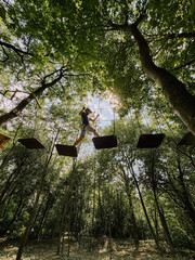 Park linowy. Adrenalina między drzewami. Aktywność nad ziemią. Przygoda dla odważnych. Młody chłopak wspina się.  © Anita