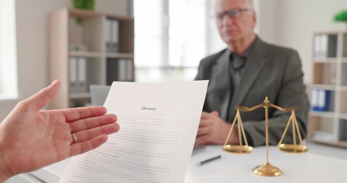 Client presents divorce document to lawyer for consultation. Justice scales and legal papers frame separation, agreement and settlement discussion today. Clear guidance for a new beginning.