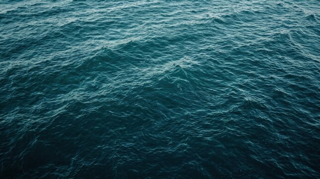 Deep teal ocean surface filling the frame with subtle ripples and reflected light, abstract seascape photography, rich navy and turquoise palette, natural wave texture, soft highlights and tranquil