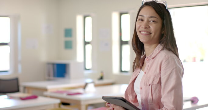 Young teacher holding a tablet in a classroom in high school