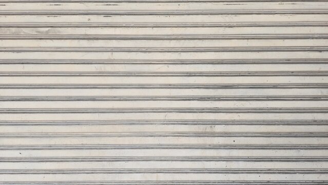 Old dusty metal roller shutter door with stains texture. Grunge rusty metallic rolling gate backdrop background. Abstract horizontal lines pattern on dirty rusty metal door.