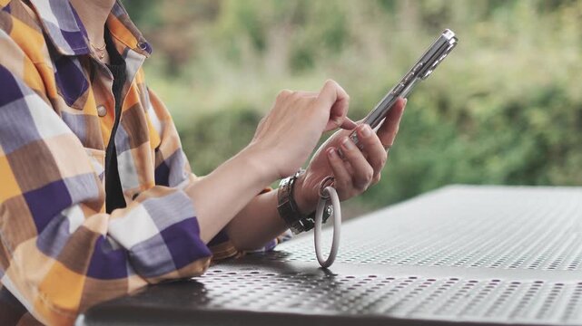 Woman Using Smartphone Outdoors with Natural Green Background in Slow Motion