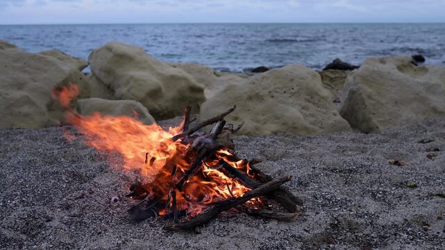 Bonfire Burning on Pebble Beach at Dusk with Sea Waves Sound