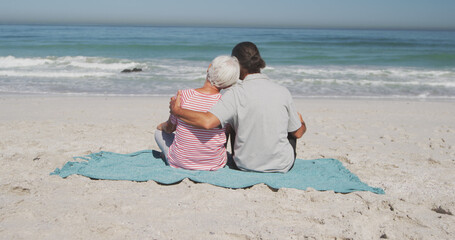 Senior caucasian couple sitting on blanket and embracing on beach © WavebreakMediaMicro