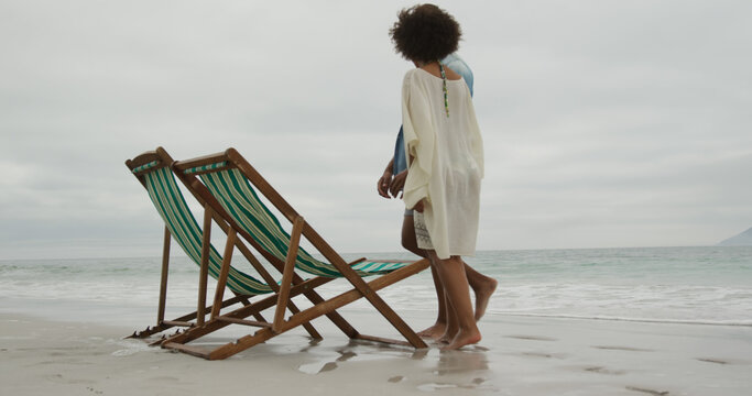 African american couple sitting in deckchairs on beach