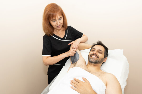 Man receiving underarm waxing from a professional esthetician