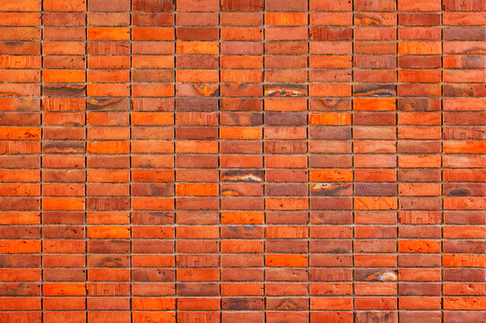 Vibrant orange and red brick wall texture background with stacked modern clinker pattern and ample copy space