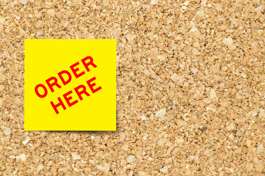 Yellow note paper with word order here on cork board background with copy space