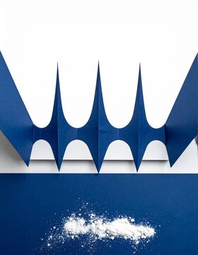 White powder and cut blue paper shapes on a deep blue surface, minimal abstract flat lay with copy space