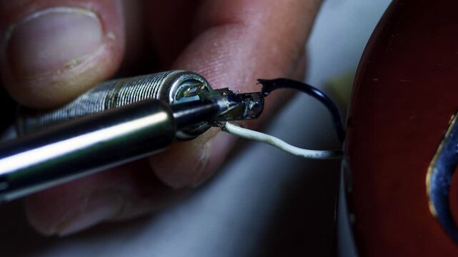 Soldering iron tip melting wire onto audio jack input close up, ideal for professional guitar repair shop promo video, online electronics repair masterclass banner or musical equipment service website