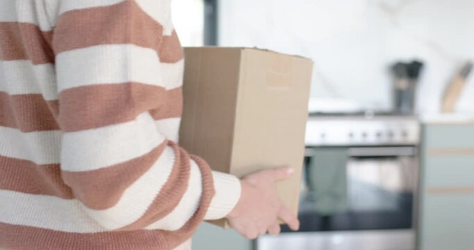 Picking up box, adult carrying box, rotating barcode out and placing beside phone in kitchen
