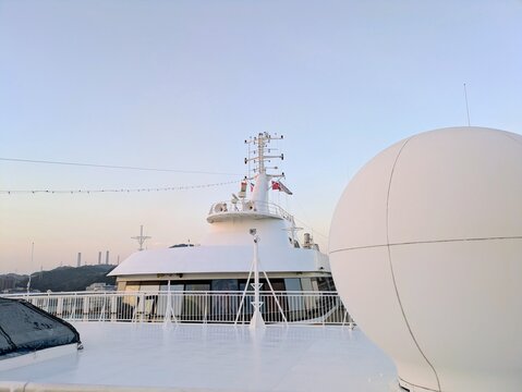 Cruise ship upper deck featuring white satellite communication radome and navigation mast