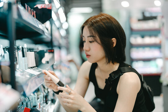 Adult woman shopping for cosmetics in a modern beauty store choosing makeup trend products on a shelf