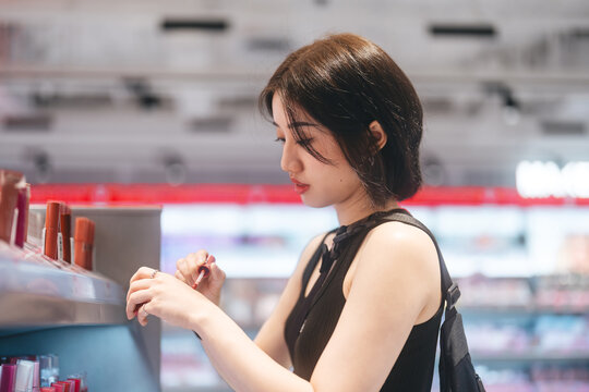 Adult woman shopping for cosmetics in a modern beauty store choosing makeup trend products on a shelf