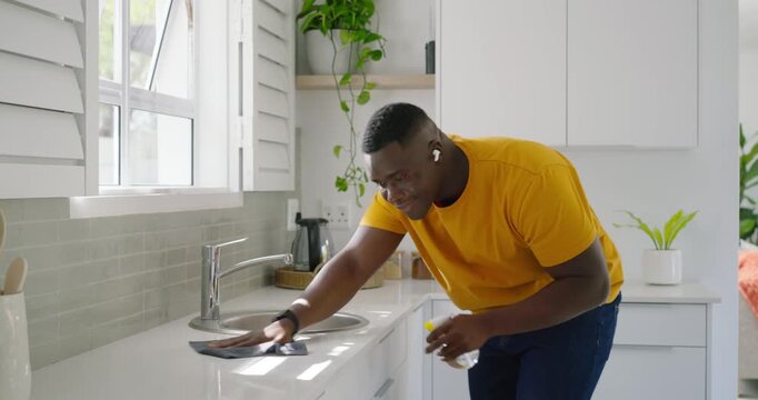 Mid adult man reaching for spray bottle, cloth, spraying, wiping home counter, cleaning, copy space