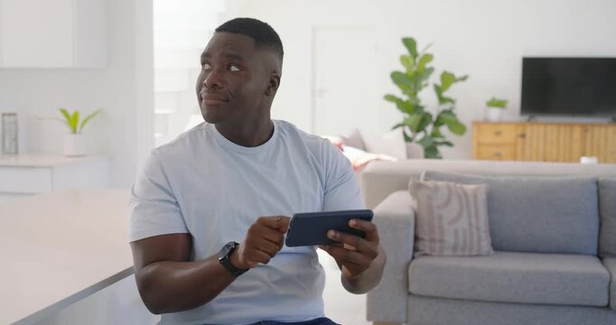Mid-adult African man launching app, tapping and swiping smartphone at home to select media for TV
