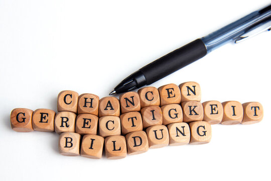 Kuli und Holzw&uuml;rfel mit Buchstaben, die zusammen die Begriffe Gerechtigkeit, Chancen und Bildung bilden, Symbol der sozialen Teilhabe, des Zugangs zu Wissen und fairer Startbed. id. Gesellschaft.