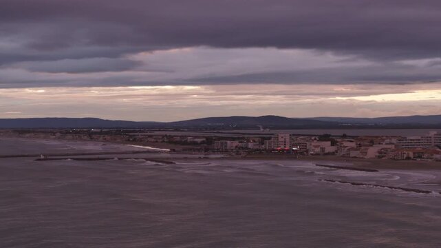 Carnon coastline with breakwaters bird and distant hills under clouds