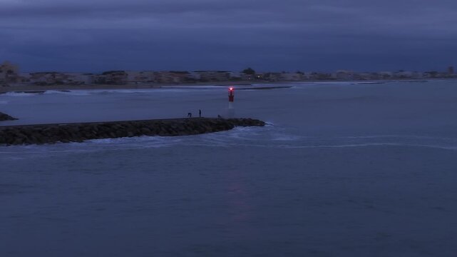 Carnon breakwater with red and white lighthouse and people