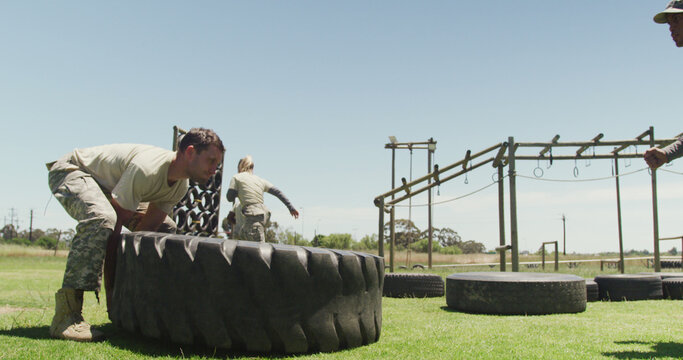 A fit soldier trains by flipping a tire outdoors, embodying a vigorous military lifestyle.