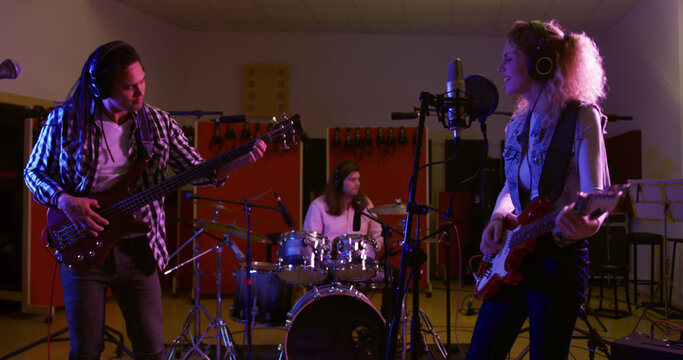 A diverse band records a song at a studio session.