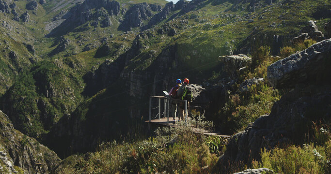 Caucasian couple wearing helmets and trekking in mountains