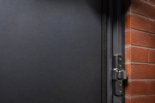 A dark gray wall meets a black-framed door next to an exposed red brick wall.